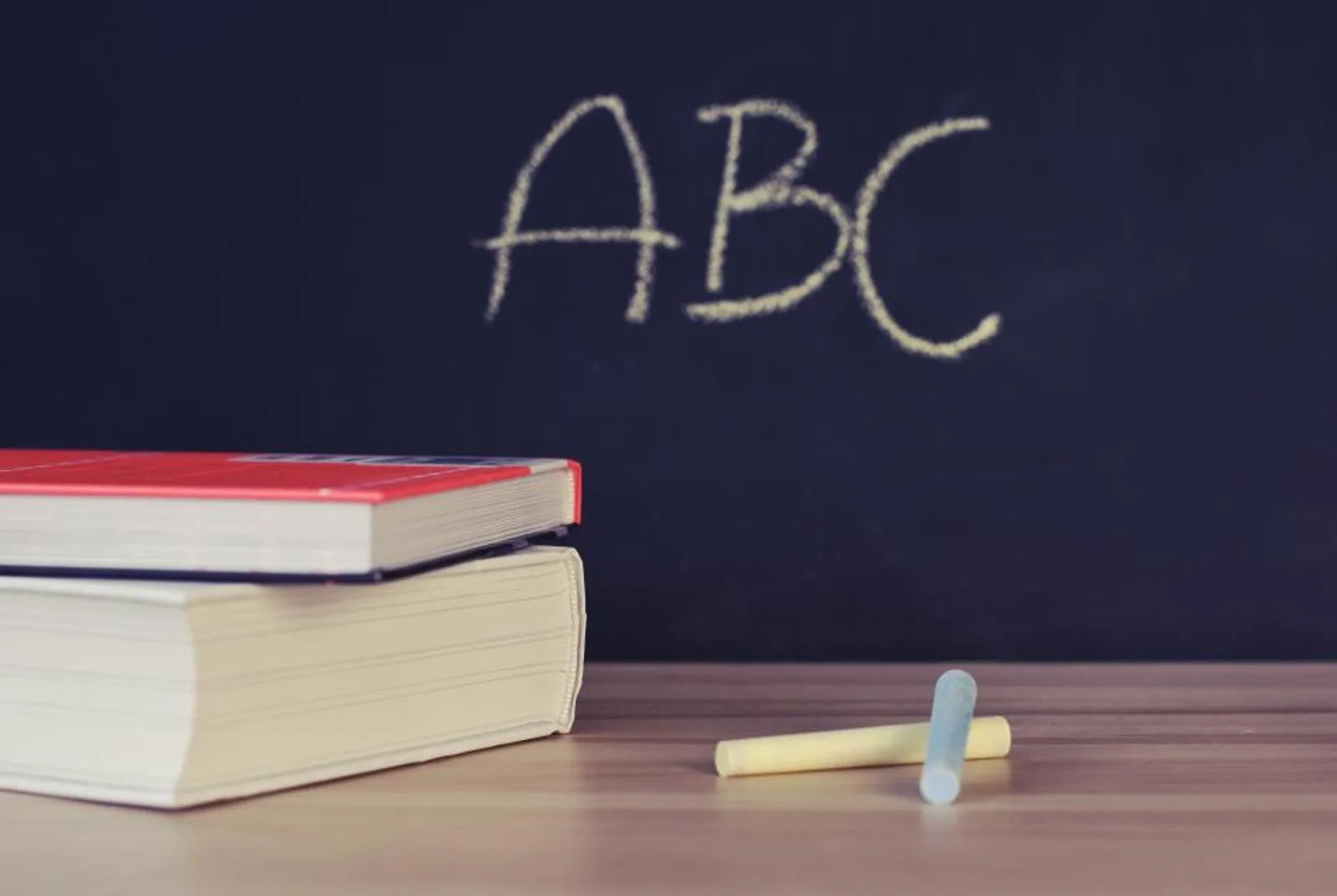 Books on a desk in front of a chalkboard
